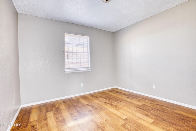 unfurnished room featuring wood-type flooring and a textured ceiling