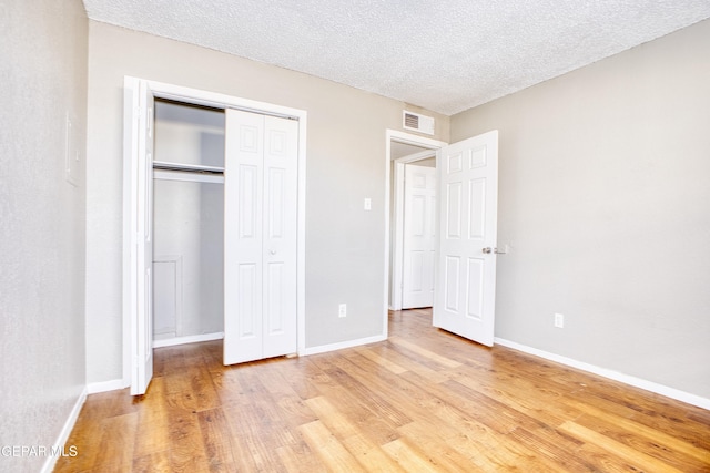 unfurnished bedroom featuring a closet, a textured ceiling, and light hardwood / wood-style flooring