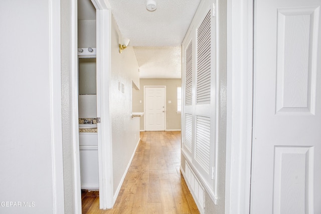 hallway featuring sink, a textured ceiling, and light hardwood / wood-style floors