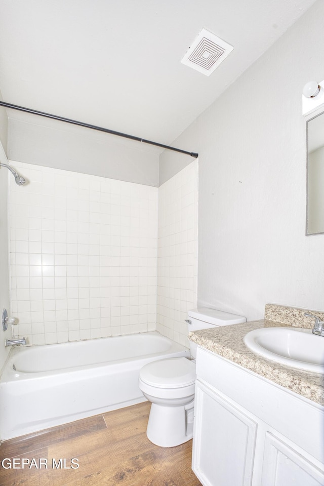 full bathroom with toilet, tiled shower / bath, hardwood / wood-style floors, and vanity