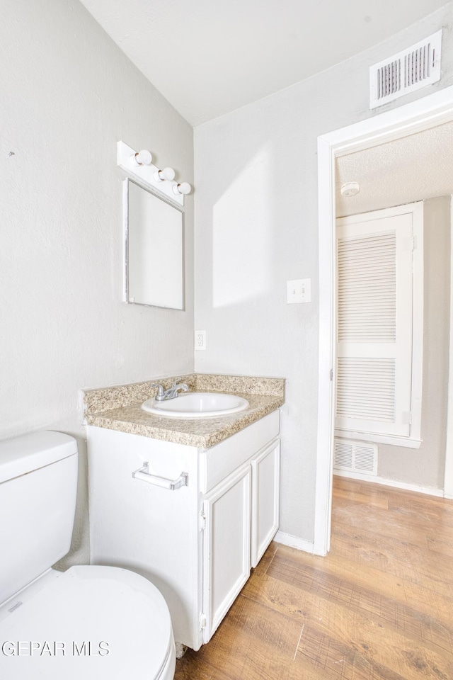 bathroom featuring toilet, hardwood / wood-style flooring, and vanity