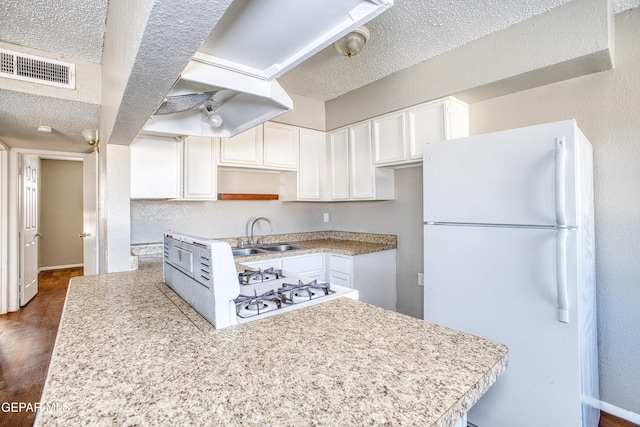 kitchen featuring sink, a textured ceiling, white cabinets, dark hardwood / wood-style flooring, and white refrigerator