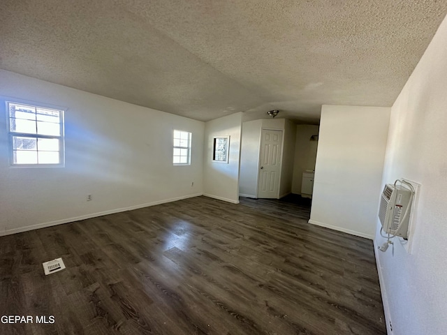 empty room with a textured ceiling, dark hardwood / wood-style floors, and a wealth of natural light