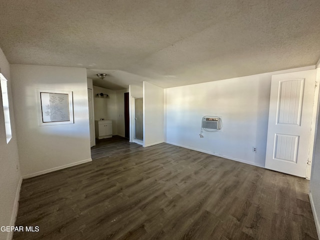 interior space with a textured ceiling, dark hardwood / wood-style flooring, and a wall mounted air conditioner