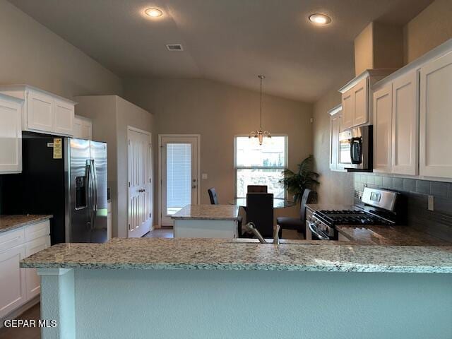 kitchen with tasteful backsplash, white cabinets, vaulted ceiling, and stainless steel appliances