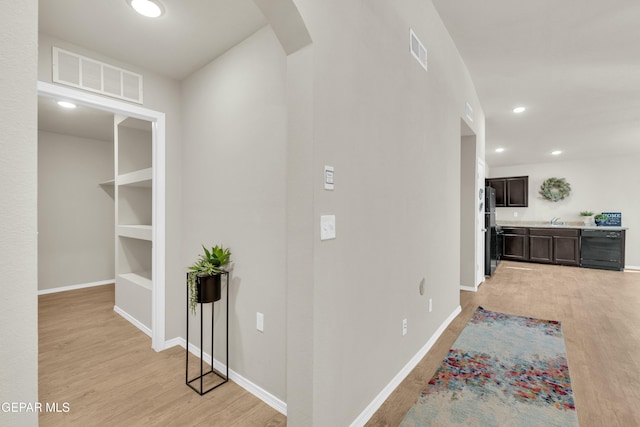 hall with built in features and light hardwood / wood-style flooring