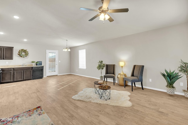 living area featuring sink, ceiling fan with notable chandelier, light hardwood / wood-style flooring, and wine cooler