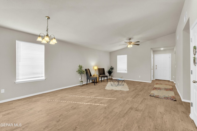 sitting room with light wood-type flooring, ceiling fan with notable chandelier, and lofted ceiling