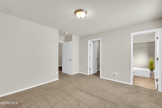 unfurnished bedroom featuring carpet flooring and ensuite bath