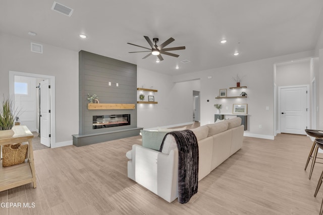 living room featuring a fireplace, ceiling fan, and light hardwood / wood-style flooring