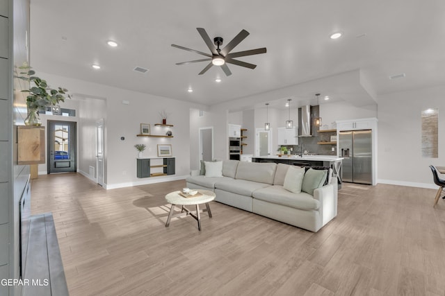 living room with sink, light hardwood / wood-style floors, and ceiling fan