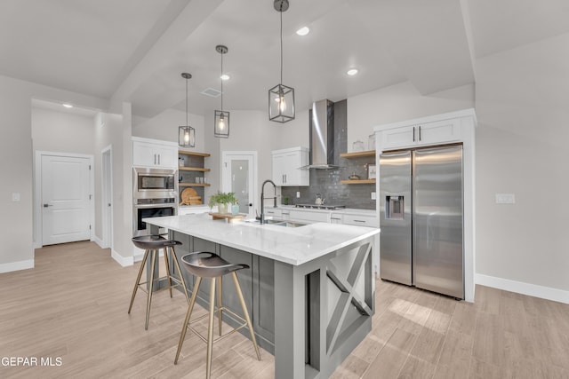 kitchen with sink, wall chimney exhaust hood, white cabinets, and appliances with stainless steel finishes