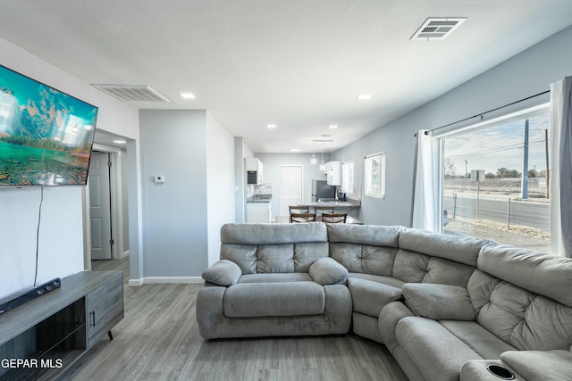 living area featuring recessed lighting, visible vents, light wood-style flooring, and baseboards