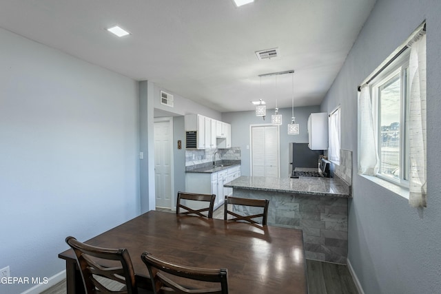 dining space with dark wood finished floors, visible vents, and baseboards