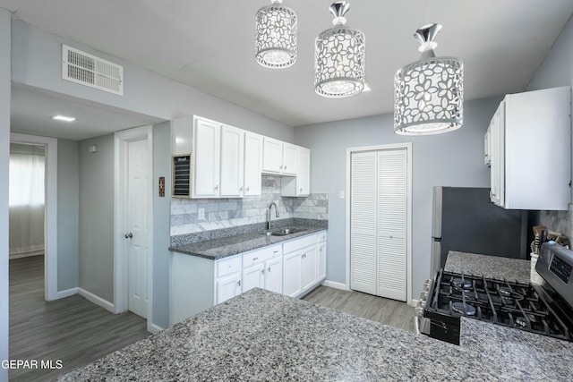 kitchen featuring visible vents, white cabinets, decorative backsplash, stainless steel appliances, and a sink