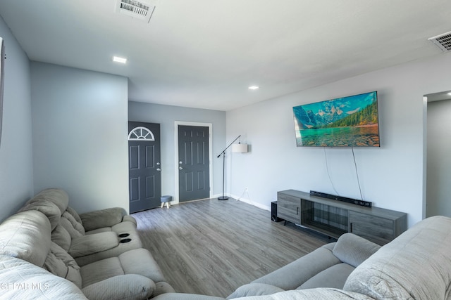 living room with baseboards, visible vents, and wood finished floors