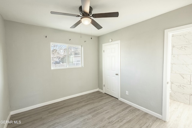 unfurnished bedroom with light wood finished floors, a ceiling fan, baseboards, and connected bathroom