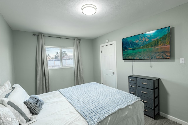 bedroom with light wood-style flooring, baseboards, and a textured ceiling