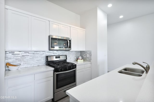 kitchen with tasteful backsplash, sink, stainless steel appliances, and white cabinetry