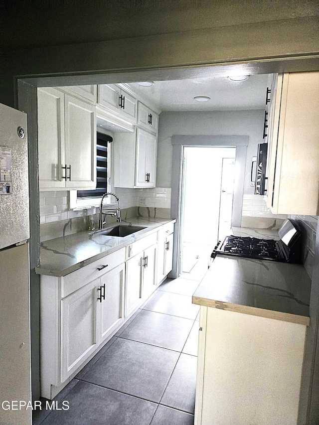 kitchen featuring sink, white cabinetry, gas range, tasteful backsplash, and white refrigerator