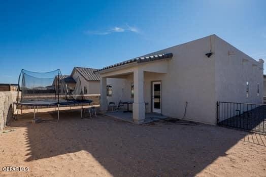 rear view of property with a patio and a trampoline