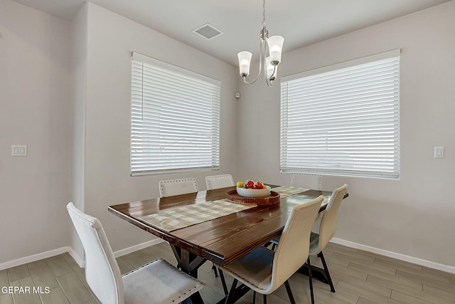 dining room with light wood-type flooring, a wealth of natural light, and a chandelier