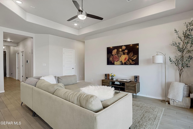 living room with ceiling fan and a tray ceiling