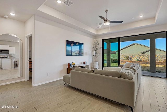 living room featuring ceiling fan and a raised ceiling