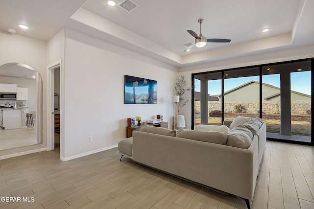 living room with ceiling fan and a tray ceiling