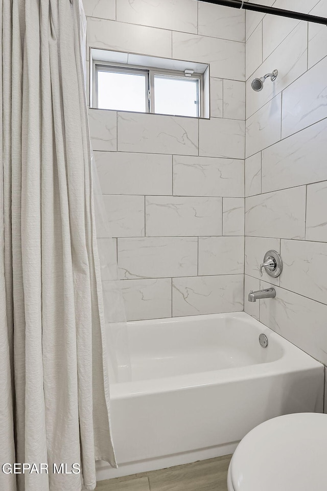 bathroom with toilet and shower / tub combo with curtain