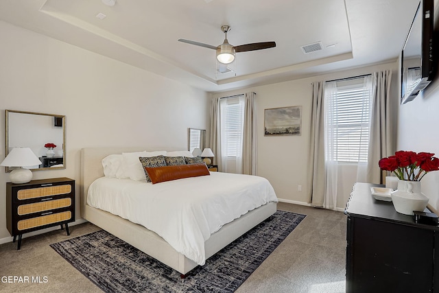 carpeted bedroom featuring ceiling fan and a tray ceiling