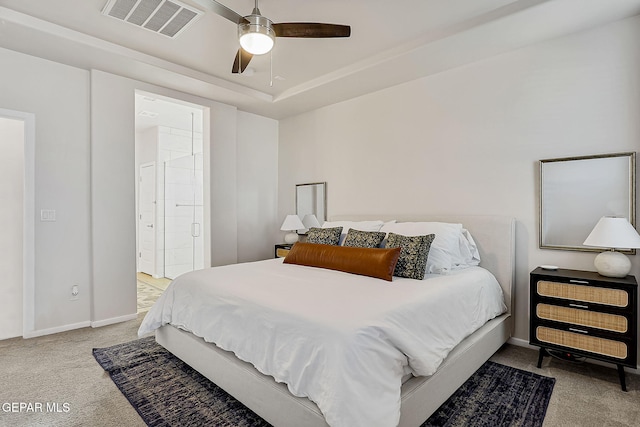 bedroom featuring ceiling fan, light colored carpet, connected bathroom, and a raised ceiling