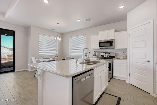 kitchen with white cabinetry, an island with sink, appliances with stainless steel finishes, hanging light fixtures, and sink