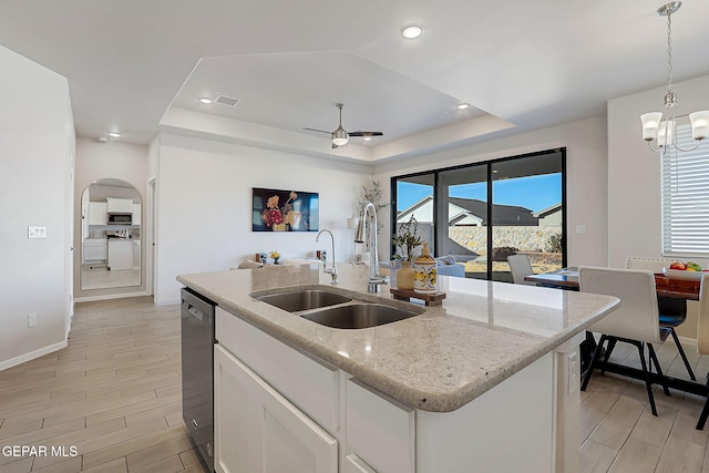 kitchen with pendant lighting, white cabinetry, an island with sink, sink, and a raised ceiling