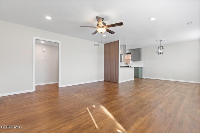 unfurnished living room featuring dark wood-type flooring, sink, and ceiling fan