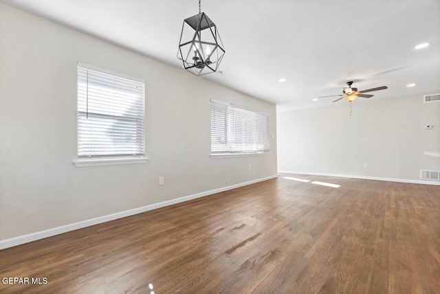 unfurnished room with hardwood / wood-style floors and ceiling fan with notable chandelier