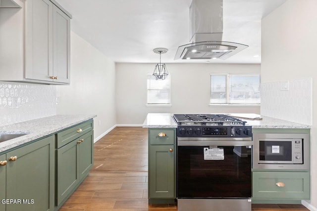 kitchen featuring gas stove, island range hood, green cabinetry, light stone counters, and built in microwave