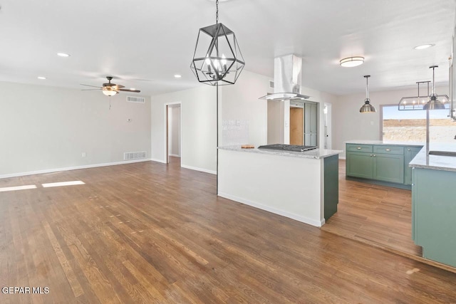 kitchen featuring island range hood, dark hardwood / wood-style floors, ceiling fan with notable chandelier, and hanging light fixtures