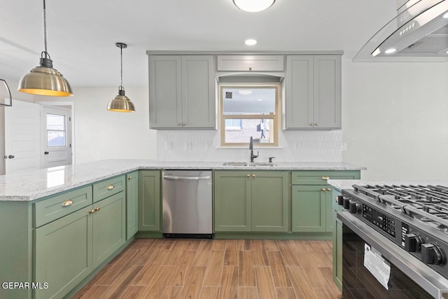 kitchen with extractor fan, appliances with stainless steel finishes, green cabinetry, light stone counters, and sink