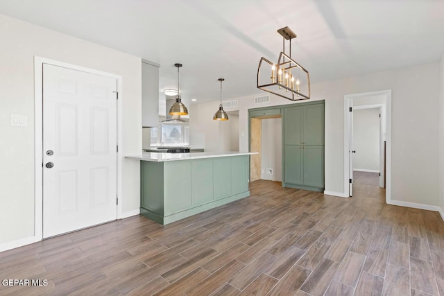 kitchen with hanging light fixtures, kitchen peninsula, a notable chandelier, and green cabinetry