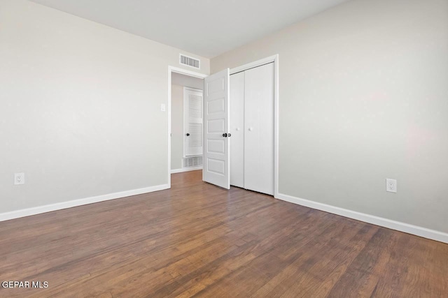 unfurnished bedroom featuring dark wood-type flooring and a closet