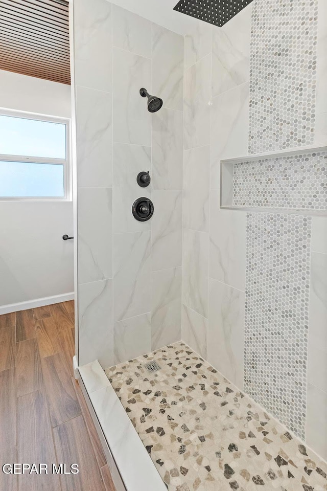 bathroom with tiled shower and hardwood / wood-style floors