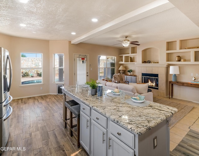 kitchen featuring a breakfast bar, a wealth of natural light, a textured ceiling, and a center island