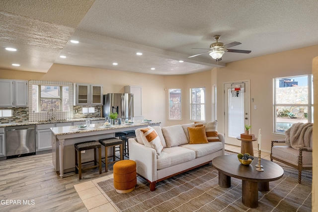 living room featuring ceiling fan, sink, light hardwood / wood-style flooring, and plenty of natural light