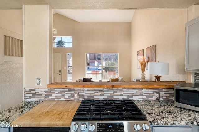 kitchen with stainless steel appliances, backsplash, and light stone countertops