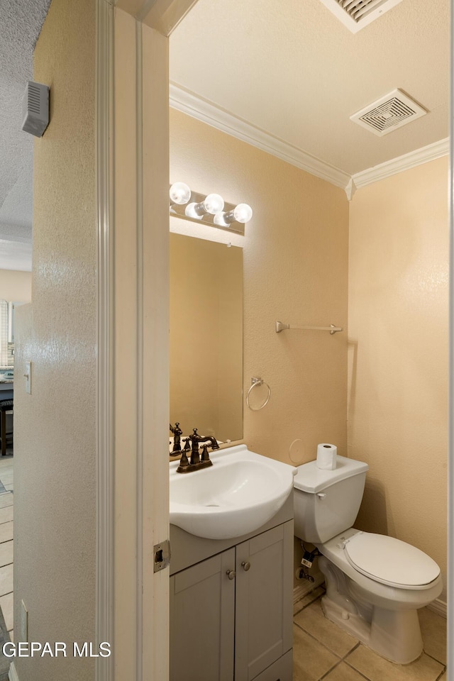 bathroom with toilet, vanity, tile patterned flooring, and crown molding