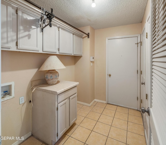 laundry room with cabinets, a textured ceiling, light tile patterned floors, and hookup for a washing machine