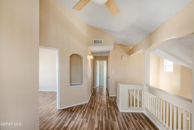 hall featuring dark wood-type flooring, a textured ceiling, and lofted ceiling