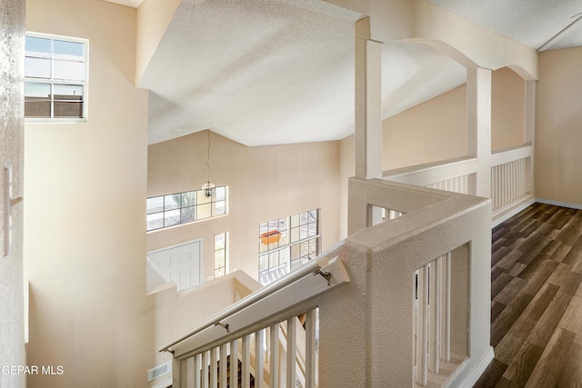 stairs with a textured ceiling and wood-type flooring