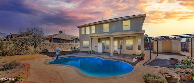 pool at dusk featuring a pergola and a patio area